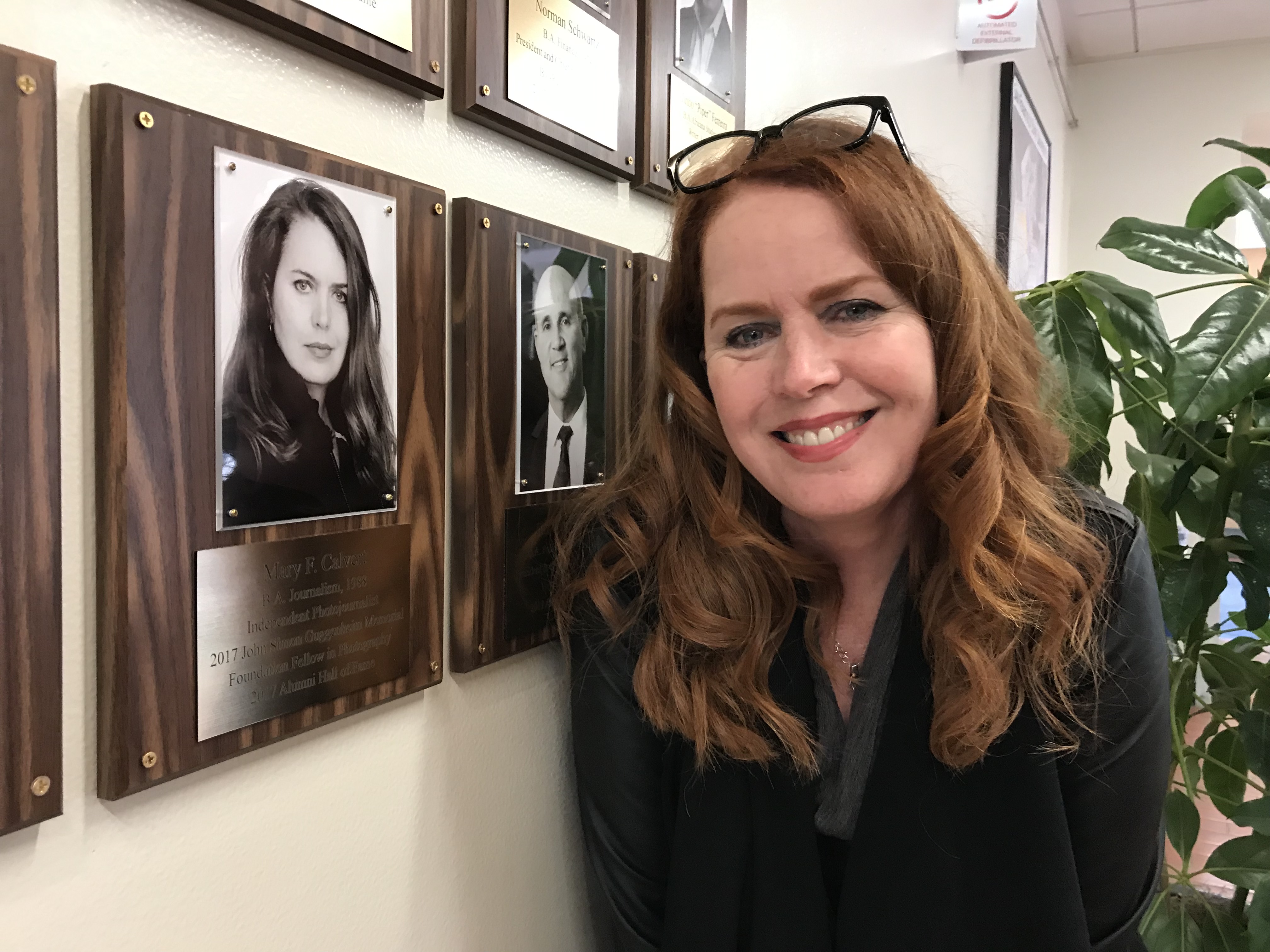 Mary Calvert stands by her photo in the Administration Building during a visit to campus in April 2019
